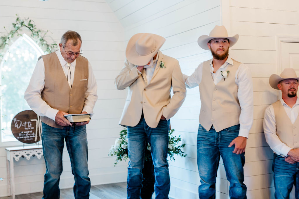 groom crying as bride walks down aisle and best man patting him on the back