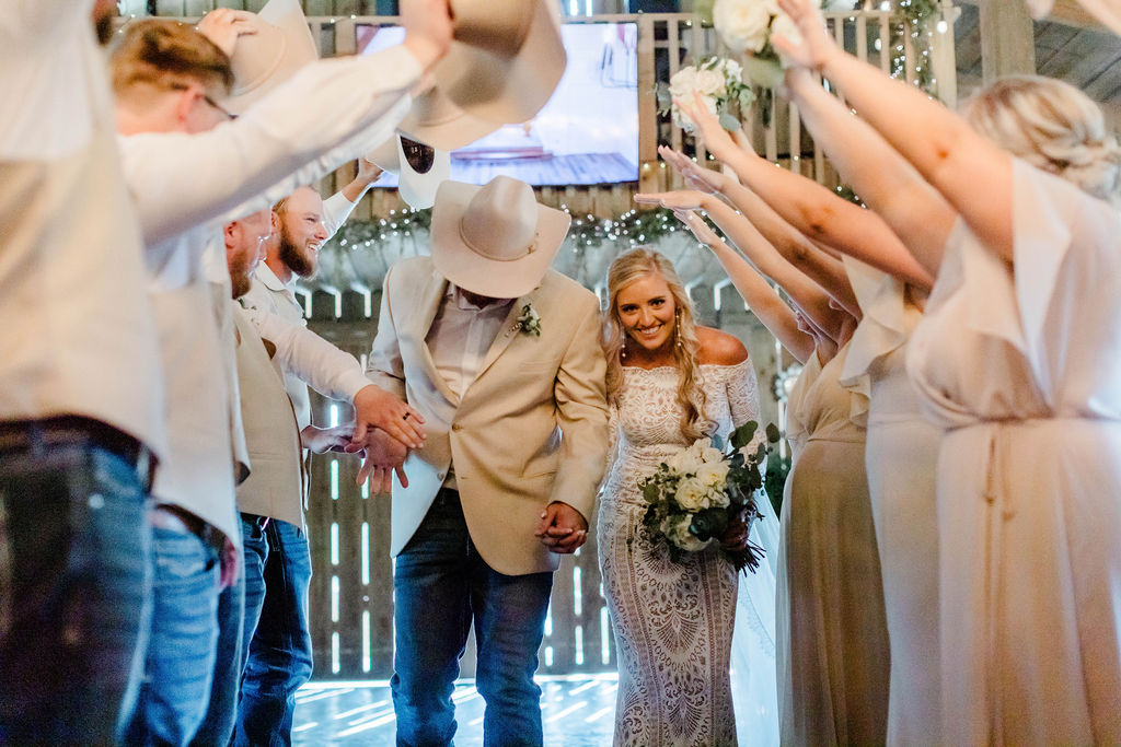 bride and groom walking through wedding party's arms